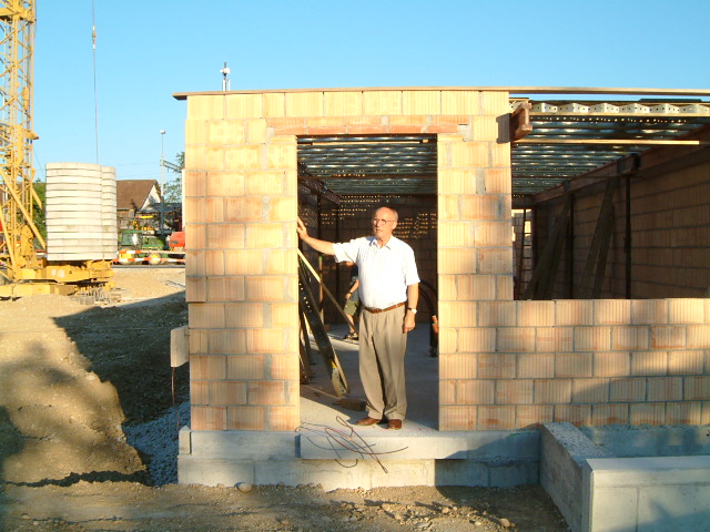 A man stands at the entrance of a brick building under construction
