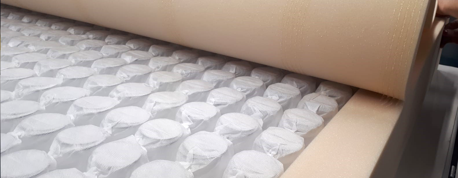 展示床垫组装时弹簧系统被泡沫覆盖的特写镜头。