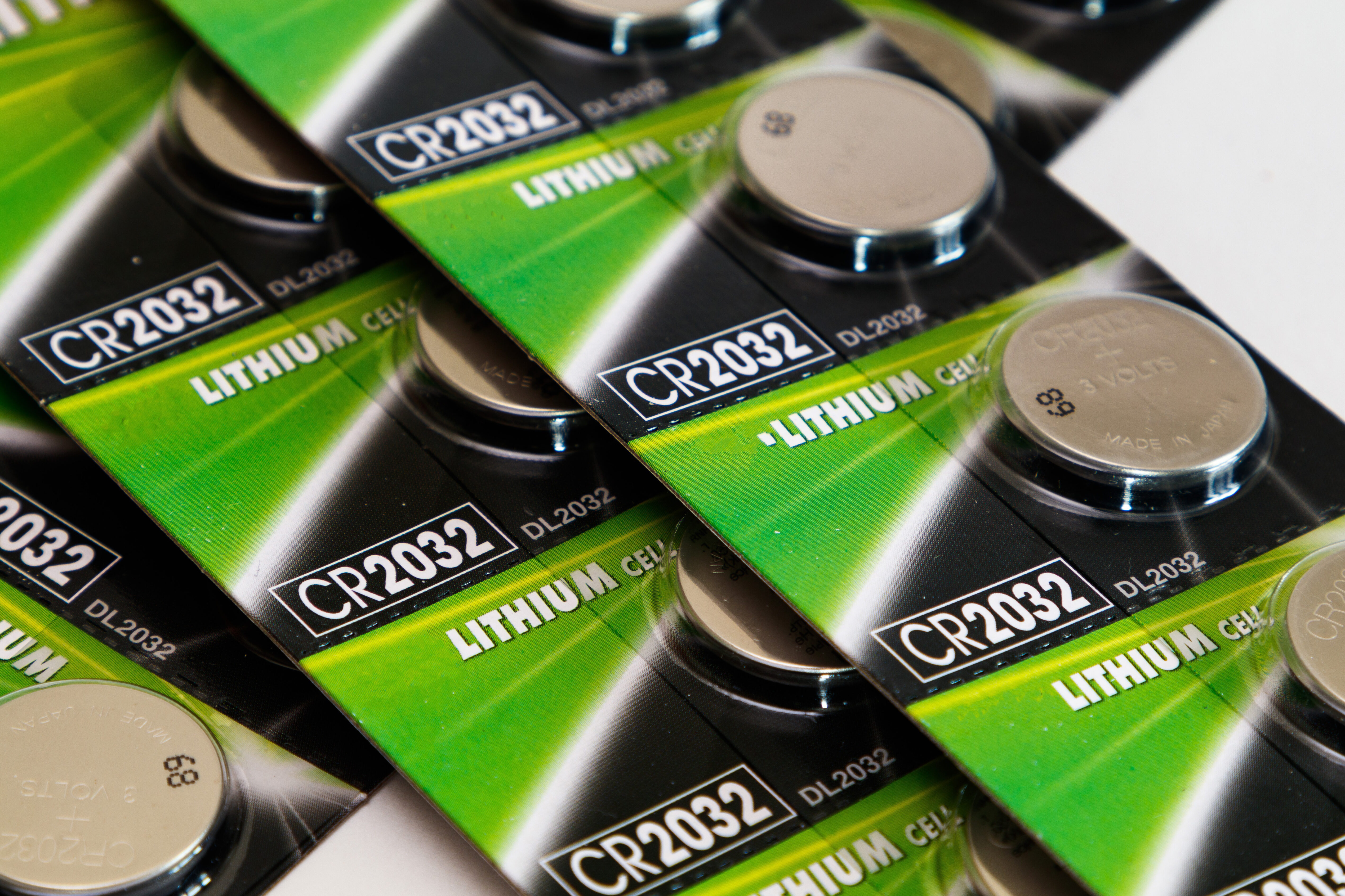 Mehrere Verpackungen mit CR2032 Lithium-Knopfzellenbatterien auf einer weißen Oberfläche.