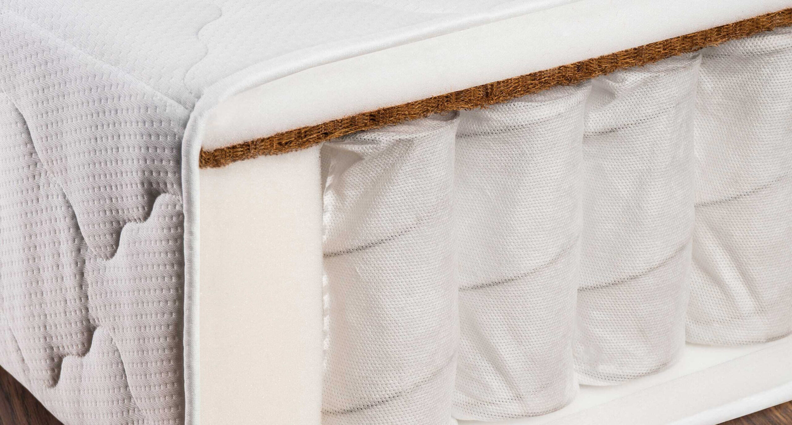 A detailed view of a mattress corner showing internal springs and a layer of coir fiber